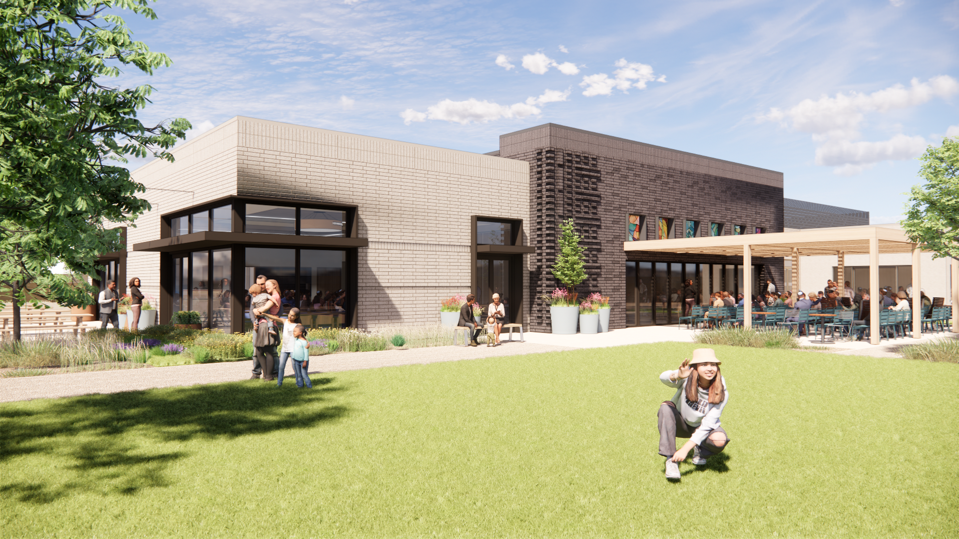 Exterior view of the new campus with green lawn, families, and outdoor gathering spaces